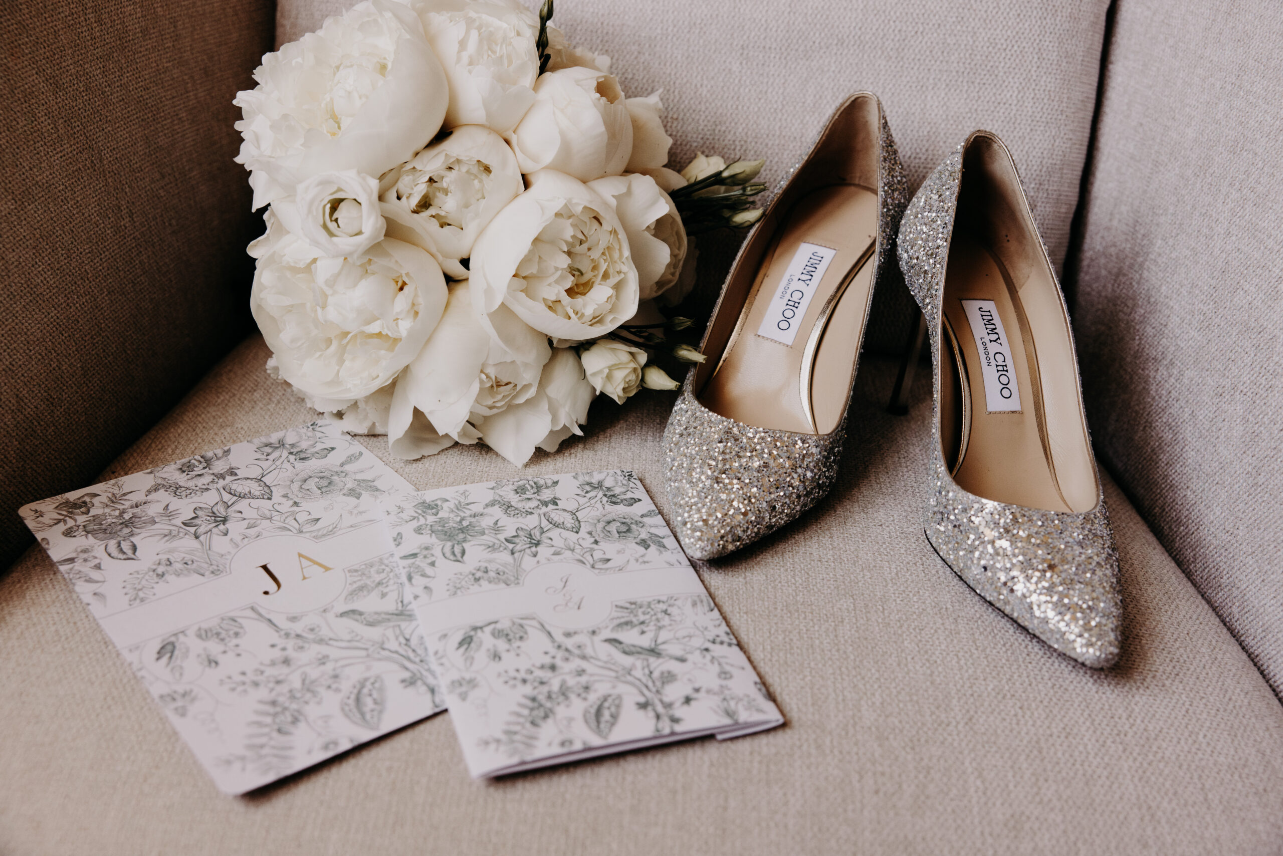 flatlay-mariage-jimmy choo-bouquet-pivoine faire part fleuri, talon escarpin pailleté argenté Jimmy Choo, bouquet de fleurs de pivoines blanches