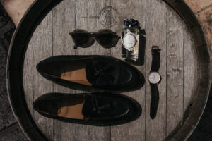 15. flatlay du marié avec ses mocassins noirs Bobbies Paris, ses lunettes de soleil sa montre et son parfum Penhaligons
