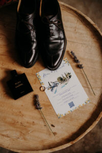 flatlay du marié avec ses chaussures, le faire-part, le parfum bleu de Chanel, les alliances