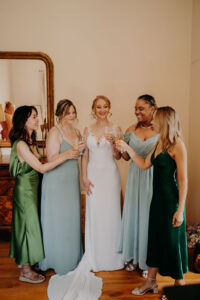 la mariée qui trinque avec des coupes de champagne avec ses témoins et demoiselles d'honneur lors des préparatif du mariage