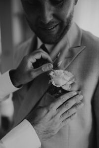 boutonnière du marié pendant les préparatif, photo en noir et blanc