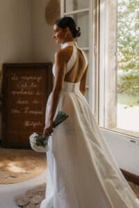 la mariée dans sa chambre avec sa robe de mariée et son bouquet de fleurs blanches
